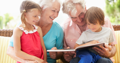 grandparents with grandchildren reading a book