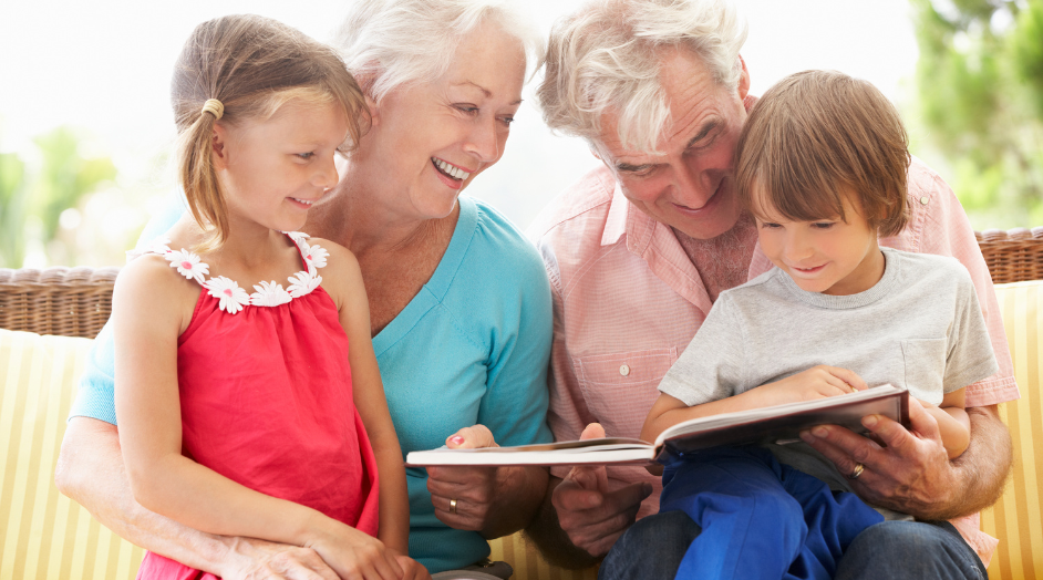grandparents with grandchildren reading a book